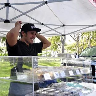 a man in a black shirt and cap standing behind a display case of cell phones