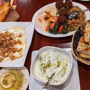 From top right, Sampler (with falafel, hummus, dolmas, and eggplant salad), bread, Jajik, lemon oil, Manti, and Kiymali Pide