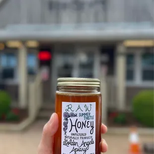 a hand holding a jar of honey