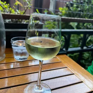 a glass of white wine on a wooden table