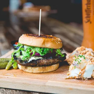 a burger and a pickle on a cutting board