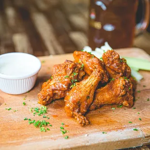 a wooden cutting board with wings and dipping sauce