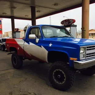 a blue and white truck parked in a gas station