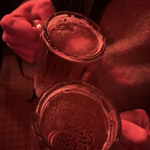 two people holding glasses of beer
