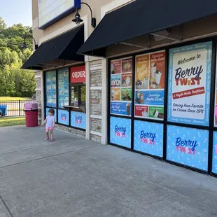 a little girl standing in front of a store