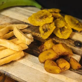 a wooden cutting board with french fries and bananas