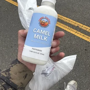 a hand holding a bottle of camel milk