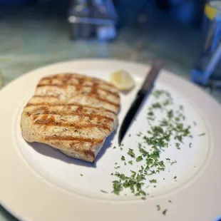 a grilled fish on a plate with a knife