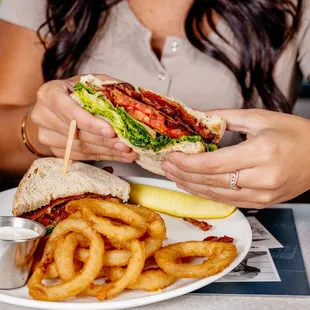 a woman eating a sandwich and fries