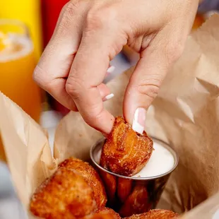 a person dipping some fried food into a bowl
