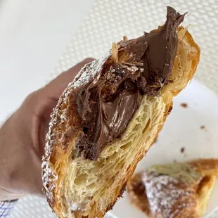 a hand holding a chocolate covered pastry