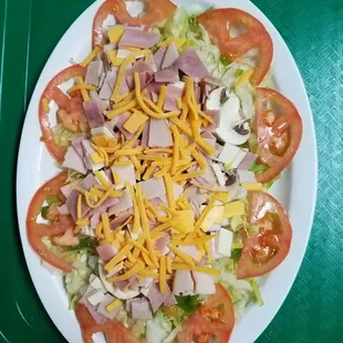 a salad with ham, lettuce, tomatoes, and cheese