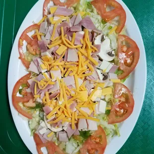 a salad with ham, lettuce, tomatoes and cheese