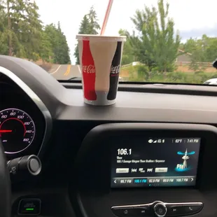 a cup of coke on the dashboard of a car