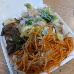 a takeout container with noodles and meat