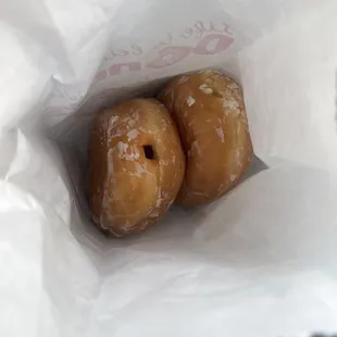 two glazed donuts in a paper bag