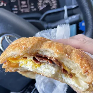 a hand holding a breakfast sandwich