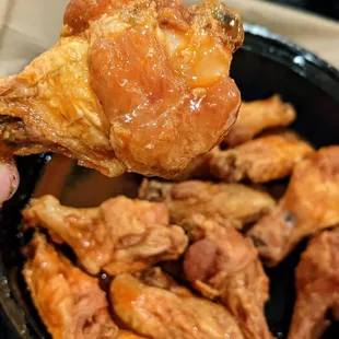 a hand holding a piece of fried chicken