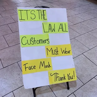 a sign that says let the law all customers must wear face mask thank you