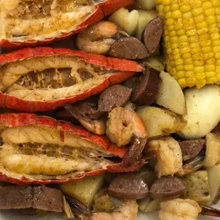 shrimp, potatoes, corn, and potatoes in a styrofoam container