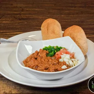 a bowl of chili and bread on a plate