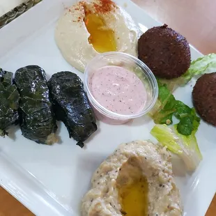 Sampler Combination of hummus, baba ghanouj, falafel and veggie grape leaves served with hot pita bread