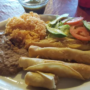 Flautas de pollo, with rice and beans garnished with shredded lettuce, sliced tomatoe, and sliced avacado.