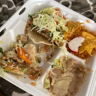 Half eaten 5 taco meal with rice and beans