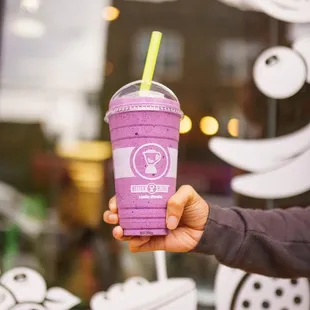 a hand holding a purple smoothie