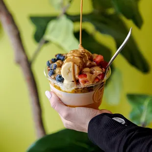 a person holding a bowl of fruit and peanut butter