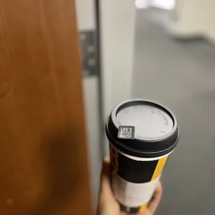 a hand holding a coffee cup