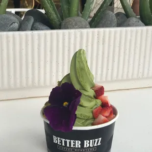 Matcha soft serve topped with strawberries, crushed pistachios, edible flower &amp; dusted with matcha powder.