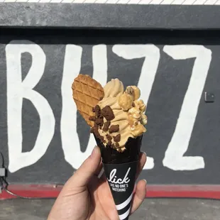 Best Drink Ever soft serve in a midnight vanilla kone topped with caramel corn, chocolate cookie crumble &amp; a butter waffle cookie.