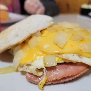 Yummy egg, cheese, and ham breakfast sandwich with grilled onions