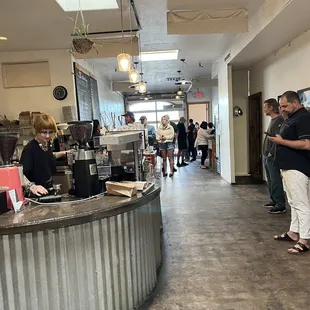 Barista Action shot and long line of eager customers to get a good cup of Joe.