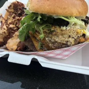 a burger and fries in a styrofoam container