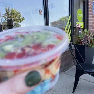 a hand holding a cup of fruit salad