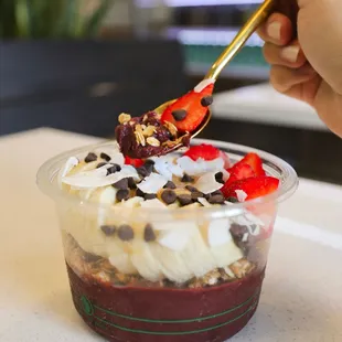a hand holding a spoon over a dessert