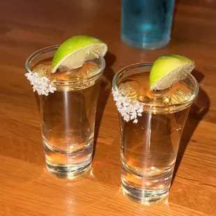 two shot glasses with lime slices and salt