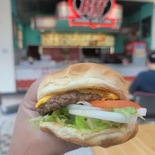 a hand holding a large hamburger