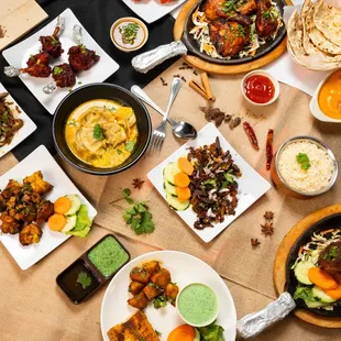 A colorful spread of authentic Nepali and Indian dishes featuring juicy grilled meats, steaming dumplings in sauce, crispy fried snacks.