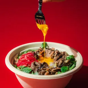 a person dipping a fork into a bowl of food