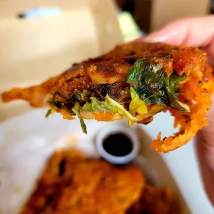 a hand holding a piece of pizza