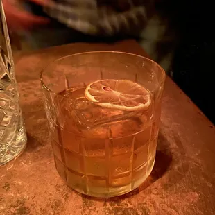 a glass of whiskey with a lemon slice in it
