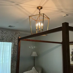 Chandelier sits on poster bed. ‍