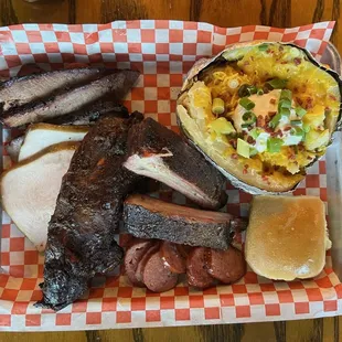 Brisket, smoked turkey, a beef rib, pork ribs, smoked sausage, stuffed potato, and a roll.