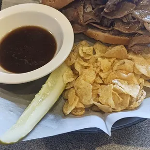 Prime rib sandwich with pickle and chips.
