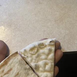 a person holding a piece of pizza