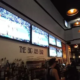people sitting at a bar watching tvs