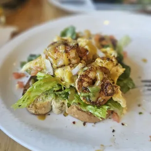 Avocado toast with light avocado, scrambled eggs, shrimp and spicy sauce drizzled on top.